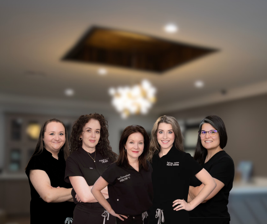 Five Premier Medical Spa team members posing in black uniforms with a softly blurred office background.